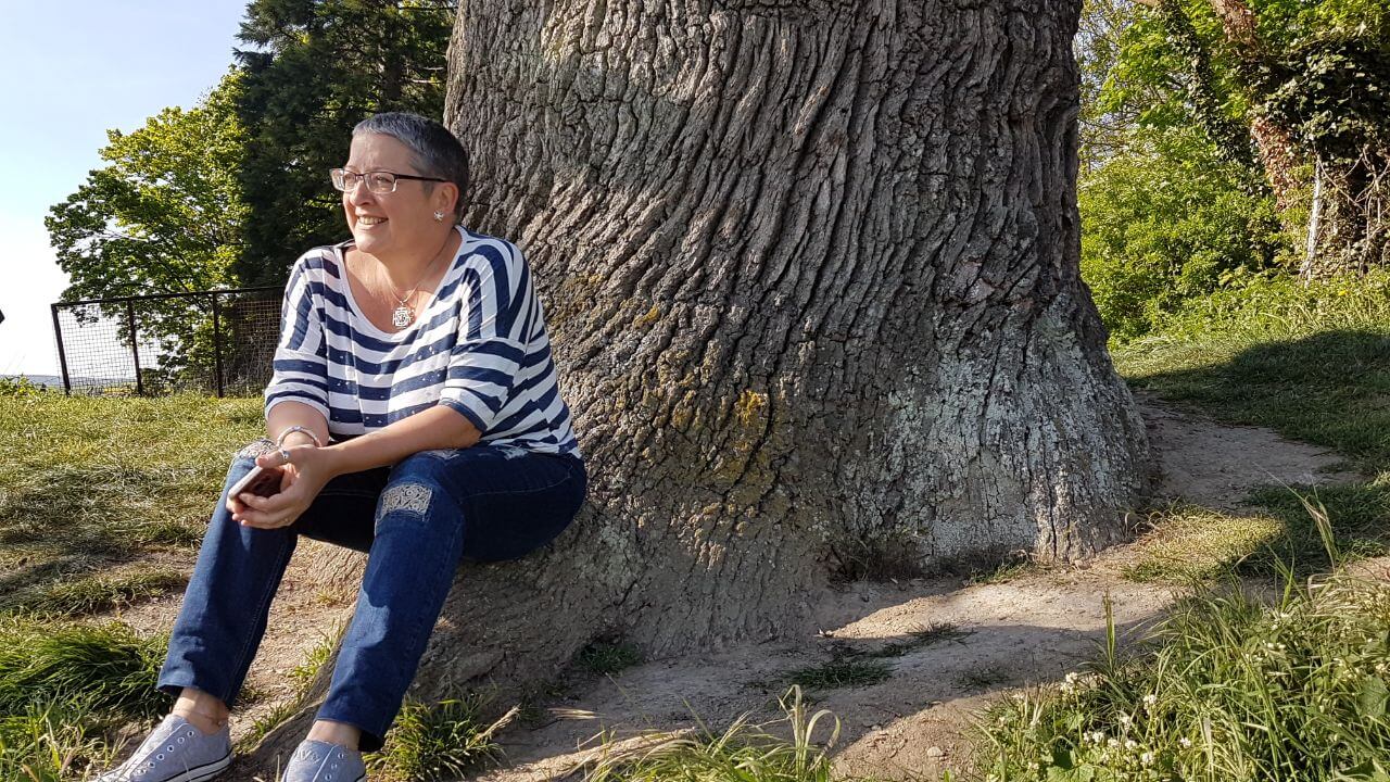 Frau sitzt vor Baum